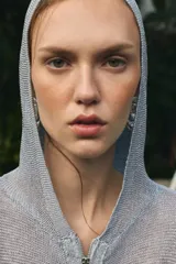 Sudadera de punto con hilo metalizado color gris, con capucha, manga larga y cierre frontal con cremallera.