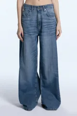 Jean de tiro medio con corte wide leg, confeccionado en denim de algodón con lavado localizado y efecto de bigotes. Presenta cierre frontal con botón y bolsillos laterales y traseros.