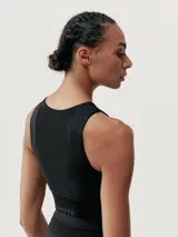Top deportivo cropped negro, de sujeción media alta, con tejido Skin_Move ligero y resistente. Diseño elegante que combina tejido de alto rendimiento con malla transpirable. Banda ancha para sujeción y copas extraíbles.