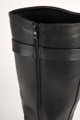 Bota de caña alta color negro, de símil cuero, con aplique de hebilla, cierre lateral y plataforma tipo tractor.