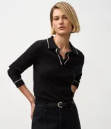 Blusa femenina negra de punto con escote en V, cuello polo y biés contrastantes en blanco en el cuello y los puños. Tiene mangas largas y corte regular.