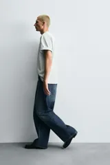 Jeans de denim de algodón, color azul oscuro con efecto lavado. Presentan un corte muy holgado (baggy fit) en toda la pierna y tiro medio. Tienen cinco bolsillos y cierre frontal con cremallera y botón.