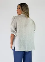 Camisa de lino color celeste, con cuello camisero, cierre frontal con botones y mangas abullonadas tres cuartos.