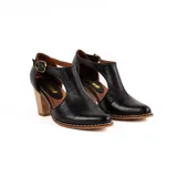 Zapato de cuero negro estilo guillermina, con diseño abierto en los laterales, taco alto de madera y hebilla metálica de ajuste.