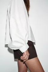 Camisa de cuello solapa y manga larga abullonada con puños ajustados. Presenta un cierre frontal con botones y un corte holgado.