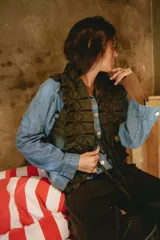 Chaleco de tweed marrón con apliques de lino y detalles de costura en zigzag con hilo negro. Presenta cierre frontal con tiras para atar en el centro.