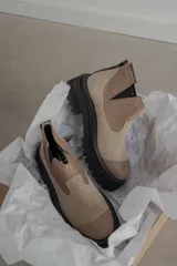 Botas tipo Chelsea de caña corta con diseño bicolor en tonos marrón y negro. Presentan paneles elásticos laterales, puntera reforzada y suela track robusta con plataforma.