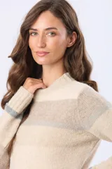 Buzo de tejido de punto con diseño de rayas horizontales en tonos beige, gris y rosado. Presenta cuello redondo, mangas largas y puños con terminación acanalada. Incluye un pequeño parche decorativo de cuero sintético en la parte inferior.