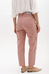 Jean gris lavado, estilo mom fit, con aplique fruncido en forma de espiral en la pierna izquierda, tiro alto, bolsillos delanteros y traseros funcionales, y cierre frontal con botón y cremallera.