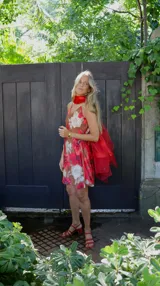 Vestido corto con estampado floral en tonos rosados y blancos sobre fondo marrón. Diseño con breteles finos y corte recto.