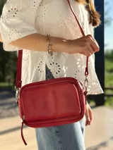 Bandolera roja de cuero con forro de tela, con bolsillo interior y exterior.