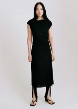 Vestido midi negro con cuello drapeado y diseño sin mangas. Presenta un corte recto con detalle de fruncido lateral en la cintura y cierre de cremallera lateral.
