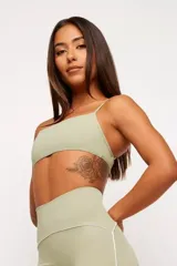 Top deportivo color verde claro, con breteles finos cruzados en la espalda y detalle de ribete blanco en el escote y bajo busto.