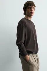 Jersey color crudo de tejido de punto, con cuello redondo y mangas largas. Corte amplio y terminaciones en rib.