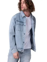 Chaqueta de denim azul claro de corte clásico, con cierre frontal de botones metálicos, cuello camisero y dos bolsillos con solapa en el pecho.