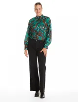 Blusa de gasa plisada con estampado abstracto en tonos verdes, azules y marrones. Presenta cuello alto, mangas largas abullonadas con puños abotonados y un corte holgado con caída fluida.