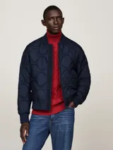 Campera bomber azul marino con diseño acolchado, cuello estilo béisbol, cierre de cremallera, dos bolsillos delanteros ribeteados, cuello, puños y bajo de punto canalé y parche con el logo de Tommy Hilfiger en la manga.