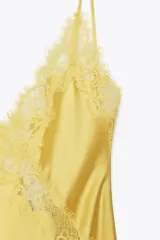 Vestido midi amarillo satinado con escote en pico, tirantes finos ajustables y detalle de encaje a tono en el escote y laterales.