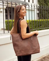 Bolso tipo tote de cuero vacuno color marrón caoba, con diseño artesanal que presenta costuras decorativas en el borde superior y asas fijas de hombro.