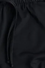 Pantalón negro de punto suave, corte holgado y pierna recta, con cintura elástica y cordón ajustable.