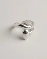 Anillo de acero quirúrgico plateado, de diseño abierto y ajustable, con detalle de gota en el frente.