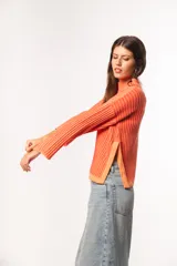 Sweater de punto acanalado color coral, con cuello alto y mangas largas con puños acampanados.