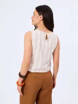 Blusa sin mangas con cuello redondo, de corte recto y diseño a rayas diagonales en tonos beige y blanco, con detalle de abertura central vertical decorada con costura ajurada.