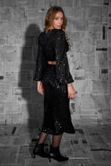 Falda midi de lentejuelas negras con corte recto y abertura lateral.