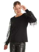 Buzo de tejido negro con mangas largas de microtul transparente, decoradas con bordados de lentejuelas y flecos brillantes. Presenta un diseño elegante con cuello redondo.