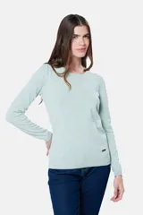 Buzo tejido en hilo de algodón color beige, con cuello redondo y manga larga. Presenta un corte clásico y un pequeño detalle metálico en la parte inferior izquierda.