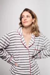 Pijama de tela tipo velvet a rayas horizontales grises y blancas, con vivos en color rojo. Incluye camisa de manga larga con botones frontales y bolsillo en el pecho, y pantalón recto con elástico en la cintura.