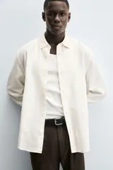 Camisa de corte regular fit confeccionada en tejido de algodón con textura de cuadrillé. Presenta cuello solapa, manga larga con puños abotonados y cierre frontal mediante botonadura.