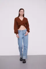 Sweater negro de tejido de punto con diseño cruzado en el frente, escote en V profundo y mangas largas con puños ajustados.