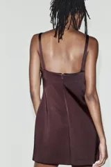 Vestido mini confeccionado en tejido satinado color bordó, de escote recto con tirantes finos y detalle de lazos aplicados en el delantero.