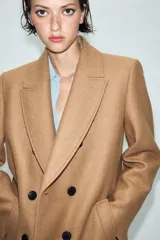 Abrigo largo negro ZARA Woman Collection de corte recto, confeccionado con hilatura de lana. Presenta cuello con solapa de muesca, cierre cruzado de doble botonadura frontal y bolsillos ribeteados en los laterales.