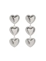 Aros colgantes dorados con tres dijes en forma de corazón. Fabricados en acero quirúrgico hipoalergénico.