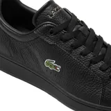 Championes Lacoste modelo Carnaby Pro, color negro con textura granulada. Presentan el logo del cocodrilo bordado en el lateral, cordones al tono y detalle metálico en el talón.
