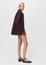 Parka color bordó, de corte recto, con cierre frontal de cremallera y botones a presión. Presenta cuello camisero de pana, bolsillos frontales de parche con solapa y mangas largas con puños ajustables. Incluye forro interior.