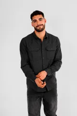 Camisa negra de manga larga con dos bolsillos en el pecho y cierre con botones. Corte clásico.