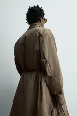 Parka relaxed fit de tejido técnico ligero, color verde militar, con cuello subido, manga larga y bolsillos de plastrón con solapa en la cadera. Cuenta con cintura ajustable con cordones y cierre frontal con cremallera oculta por solapa con botones a presión.