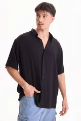 Camisa de viscosa negra de manga corta, con cuello camisero y cierre frontal de botones, de corte oversize.