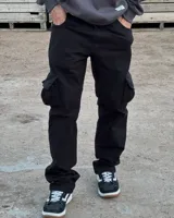 Pantalón cargo de corte baggy y silueta relajada, confeccionado en gabardina negra. Presenta bolsillos laterales tipo cargo con solapa y costuras reforzadas en las rodillas.