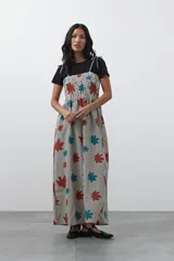 Vestido midi de corte fluido con cuerpo superior fruncido, escote recto y tiras finas regulables. Presenta un diseño estampado con hojas en tonos rojos y turquesas sobre una base de rayas verticales finas.