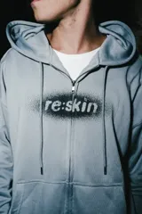 Campera de jogging celeste con cierre frontal, capucha con detalle en relieve, bolsillos tipo canguro y estampado central con efecto spray.