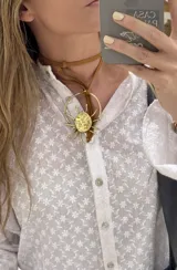 Gargantilla con tira de cuero sintético marrón y dije dorado con forma de sol.