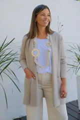 Collar largo de diseño artesanal compuesto por múltiples cordones de algodón en color crudo, entrelazados con aros y eslabones metálicos en tono dorado mate.