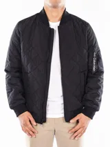 Campera bomber negra Calvin Klein con diseño acolchado en forma de rombos, cierre frontal con cremallera, cuello, puños y dobladillo acanalados, bolsillos laterales y bolsillo con cremallera en la manga izquierda.