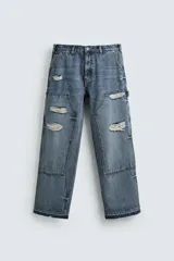 Pantalón de jean estilo carpintero con corte relaxed fit, tiro medio y pierna recta. Presenta un lavado azul medio con efecto desgastado y roturas en las rodillas. Incluye bolsillos laterales tipo plastrón, tira multifunción en la pierna, cierre frontal con cremallera y botón.