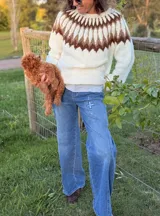 Sweater tejido a mano en mohair, de cuello redondo y manga larga. Presenta un diseño de canesú con patrón geométrico en tonos amarillo y blanco sobre una base de color marrón.