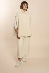 Capa color beige con textura de espiga, cuello alto con botones y aberturas laterales para los brazos. Confeccionada en lana fina sin teñir.